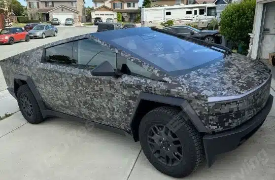 A vinyl-wrapped truck driving on a highway, showcasing a glossy custom design that enhances its appearance.