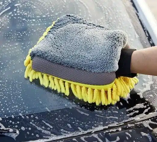 Car owner hand washing vinyl wrapped car with microfiber mitt